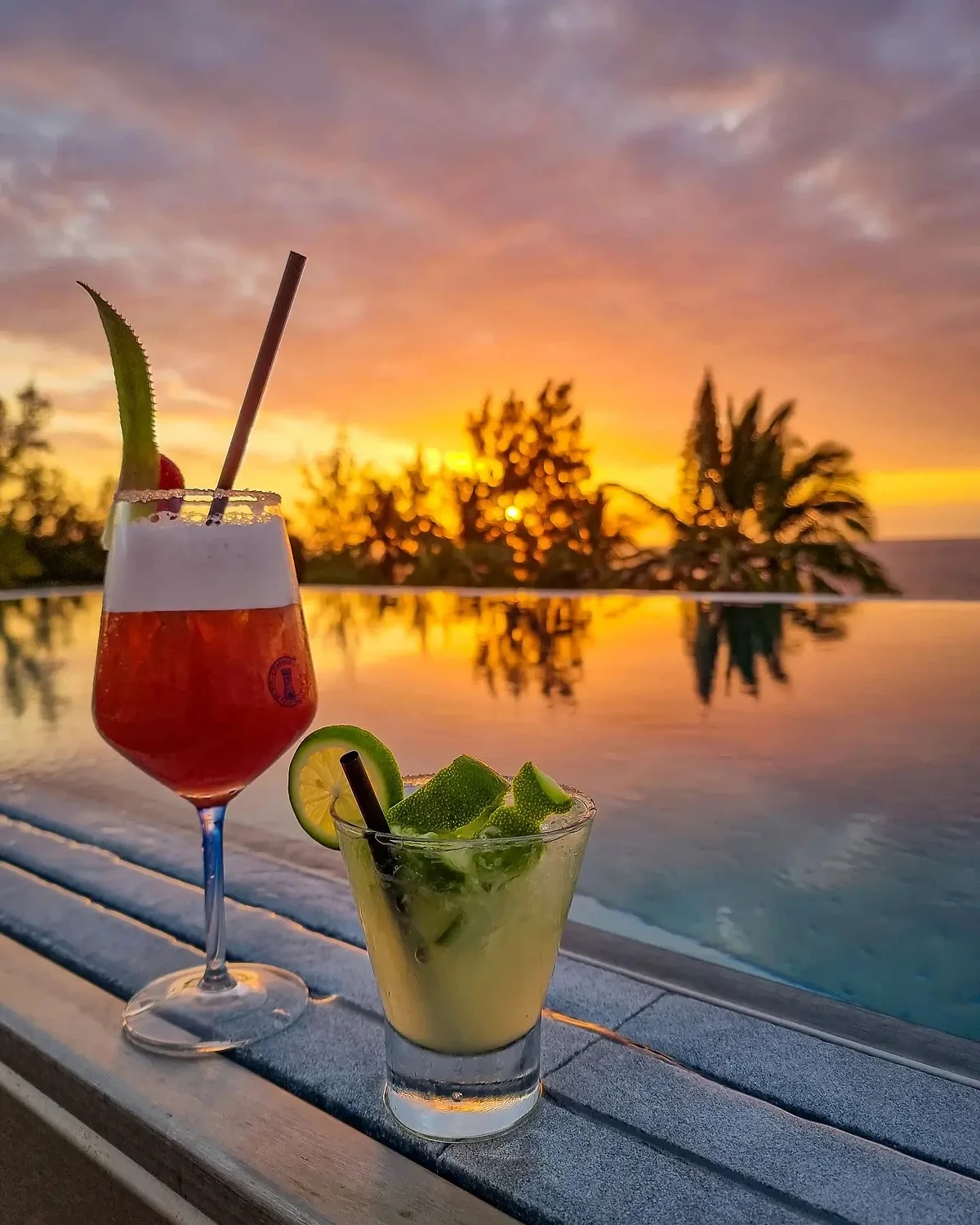 Un cocktail posé au bord du bassin au coucher du soleil