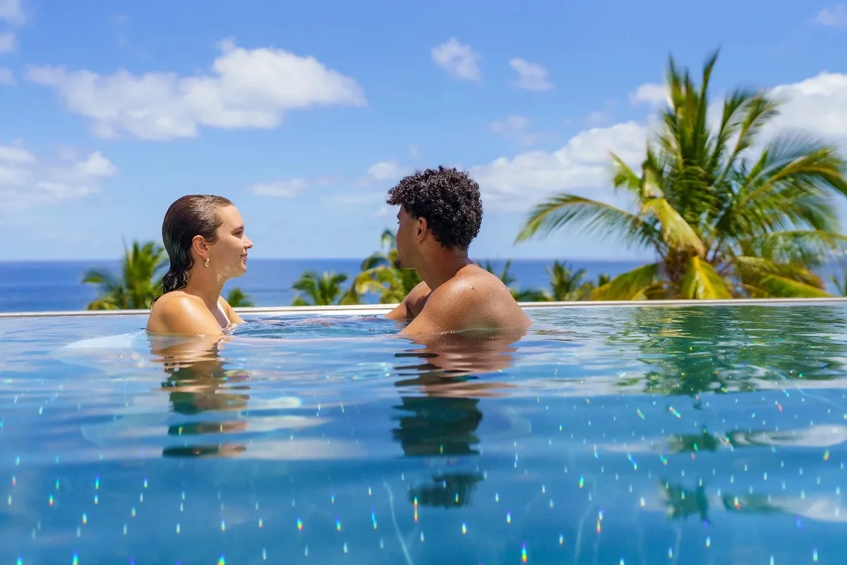 Un couple dans le bassin à débordement face à l'océan