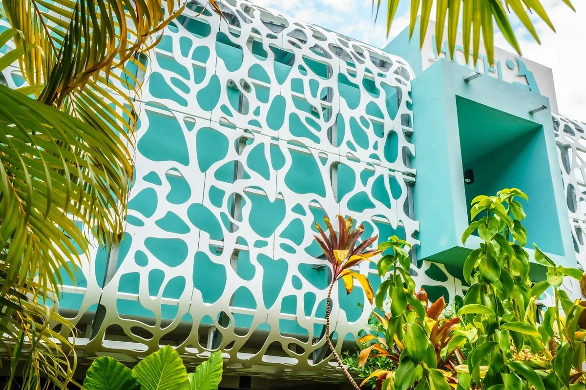 La façade ajourée de l'hôtel, ses motifs turquoise et le jardin tropical