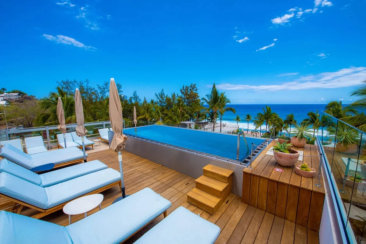 La piscine à débordement du rooftop, ses transats et l'océan Indien derrière les cocotiers
